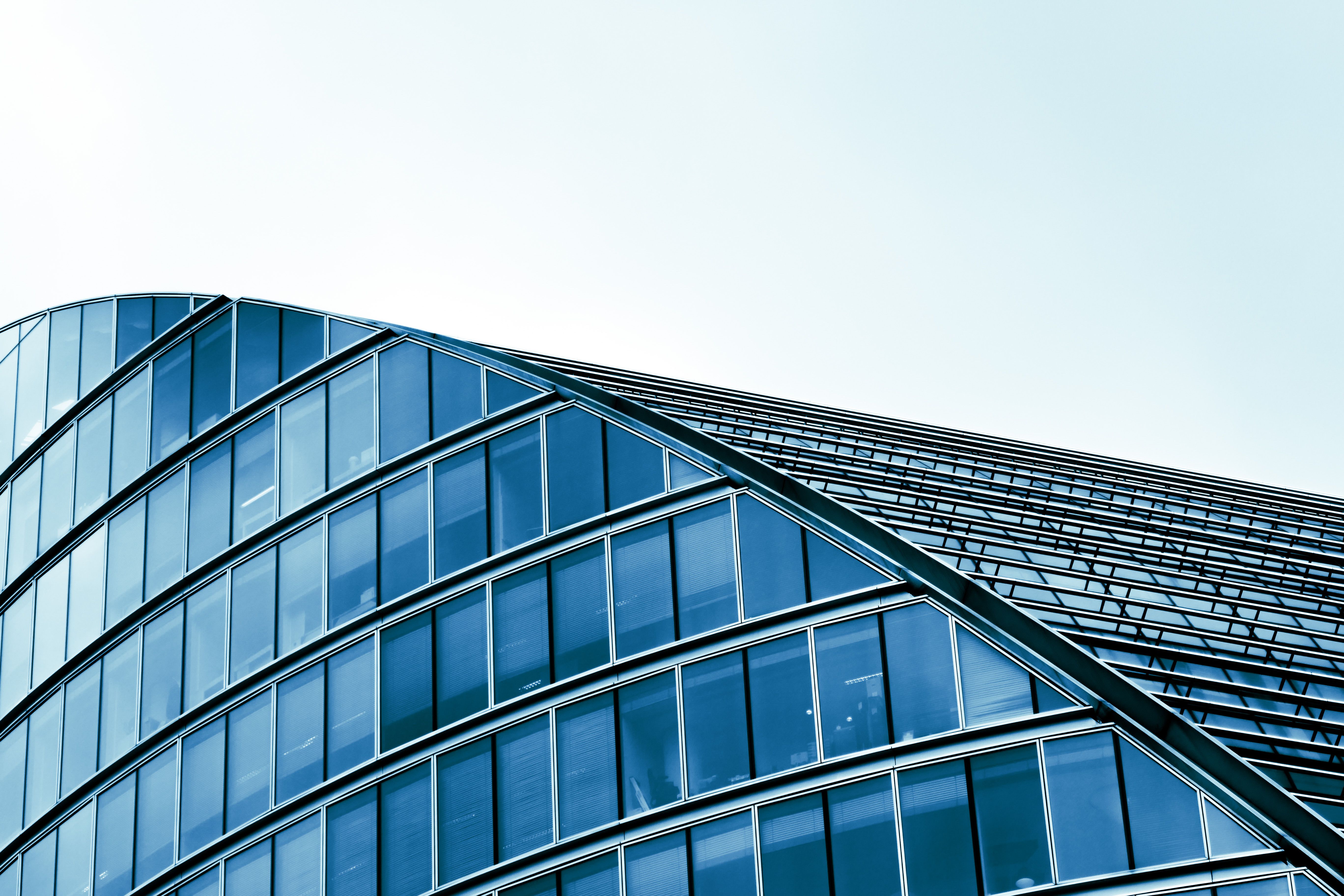 Sleek modern architecture with curved glass facade in an urban setting.
